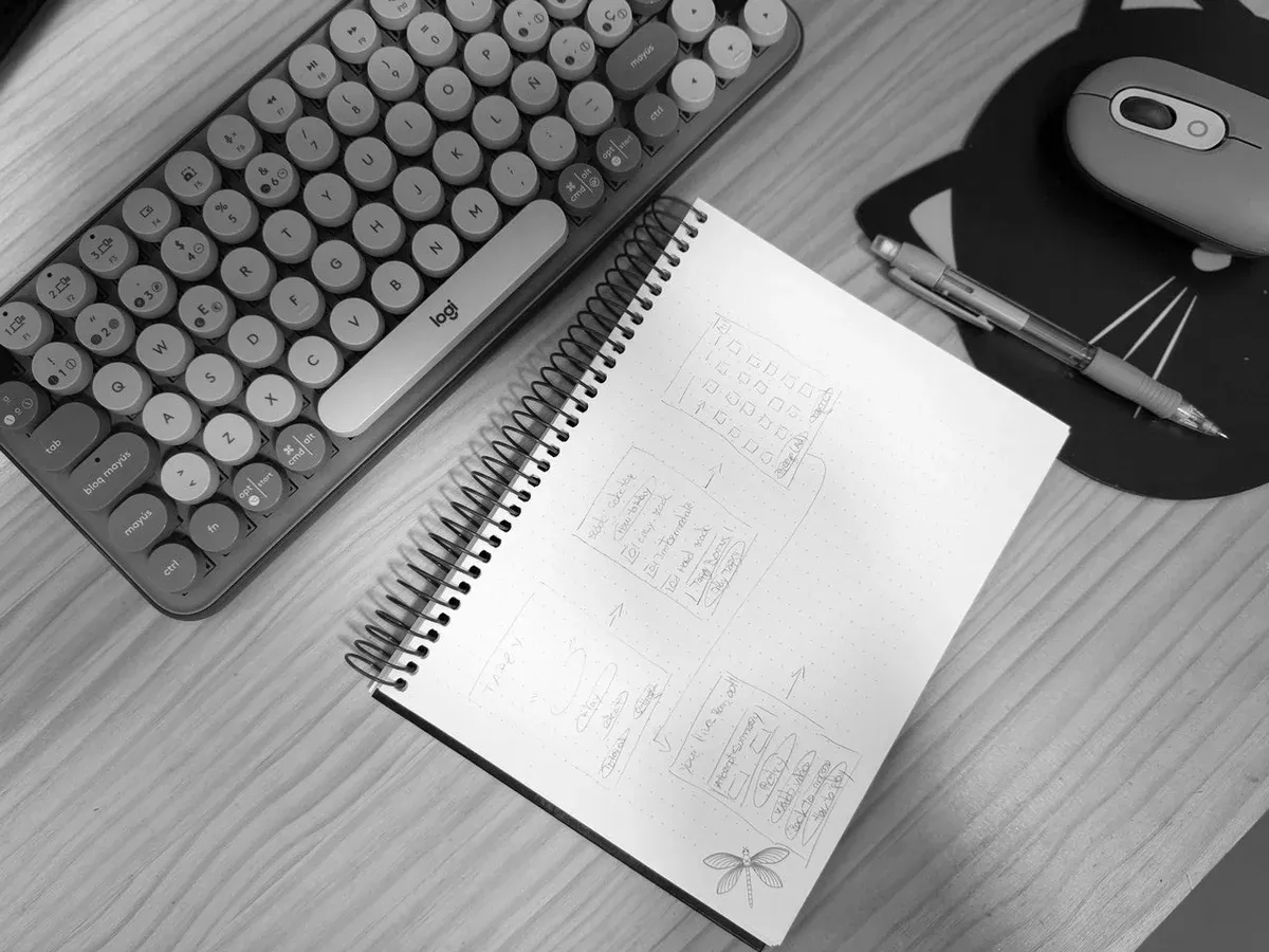 Cuaderno con bocetos de pantallas y anotaciones junto a un teclado